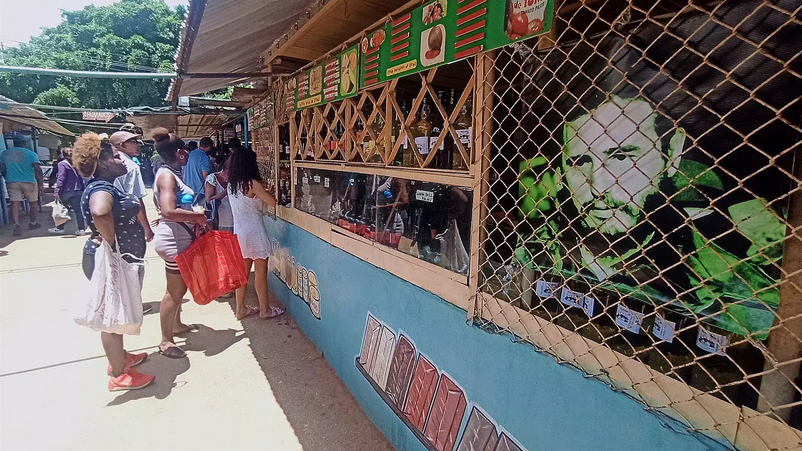 Varias personas compran en un mercado frente a una imagen de Fidel Castro